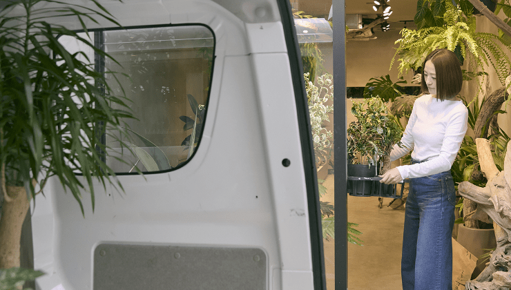 エブリイ車内から店内に植物を運ぶ女性