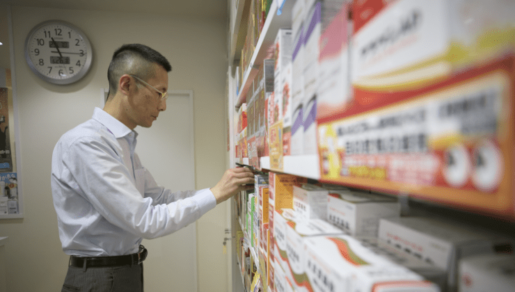 薬を陳列する薬局経営者