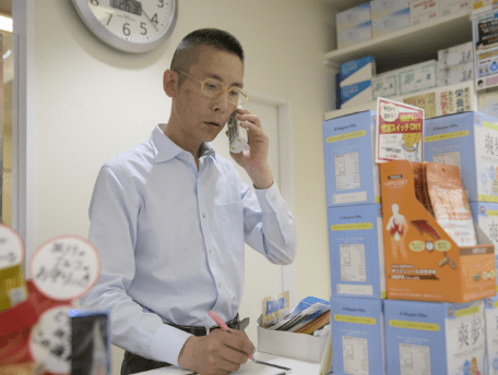 お客様と電話で会話する薬局経営者