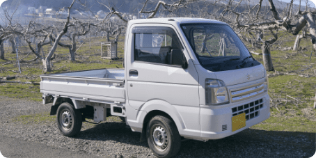 白の業務用キャリイ 果樹園内に停車するキャリイ